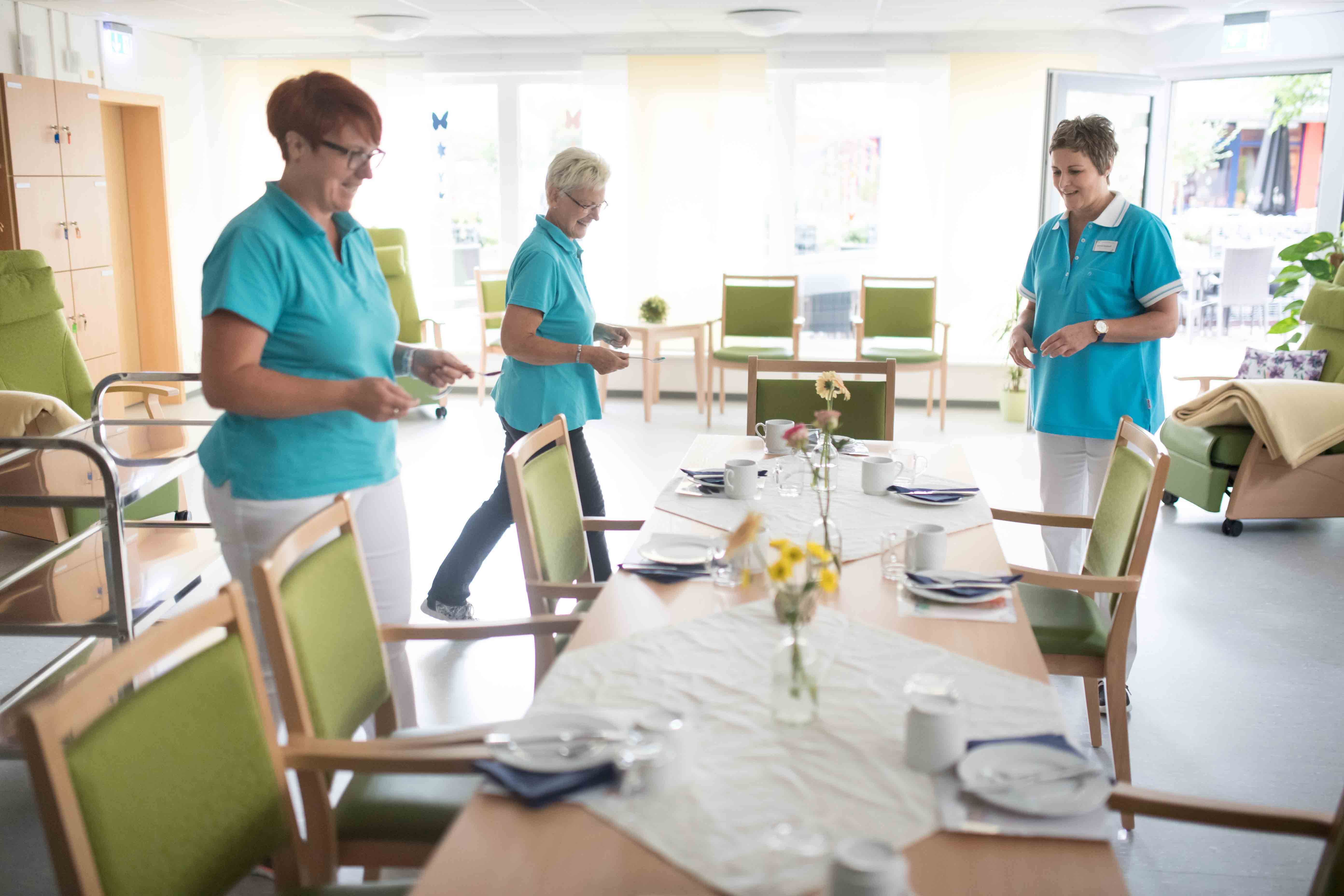 Drei Mitarbeiterinnen decken einen Tisch