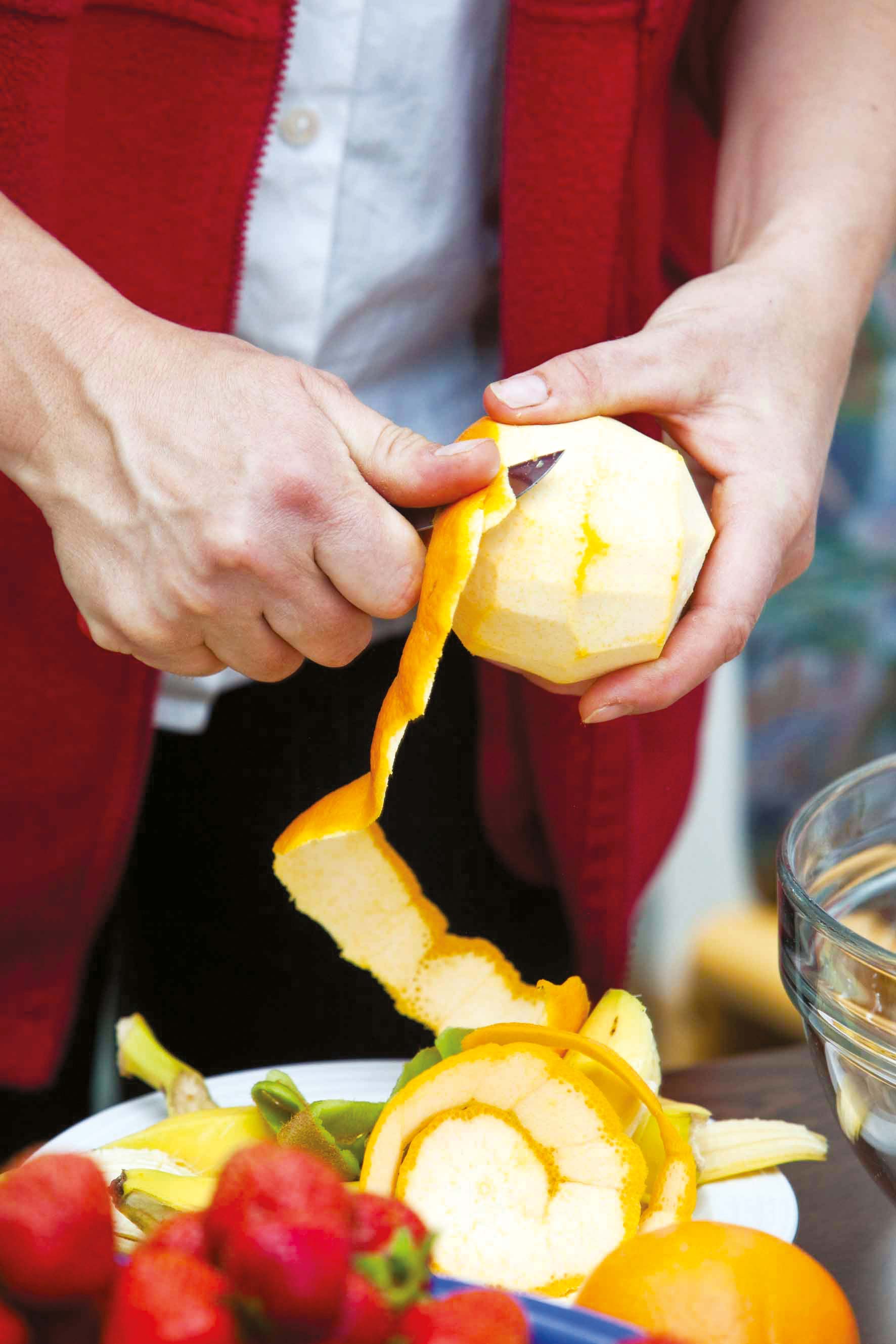 Hand schält eine Orange