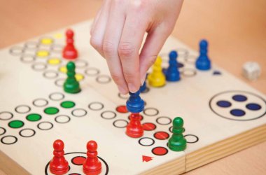 Mensch-Ärger-Dich-nicht-Spiel und Hand die eine Spielfigur setzt